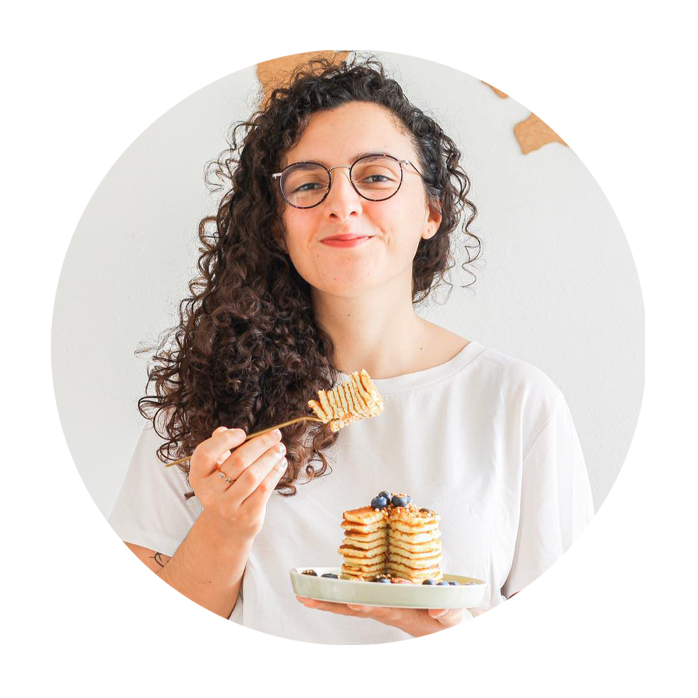 Portrait de l'autrice souriante qui mange une pile de pancakes.